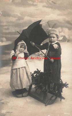Studio Shot, RPPC, Boy Holding an Umbrella over a Young Girl, Pine Cones-image